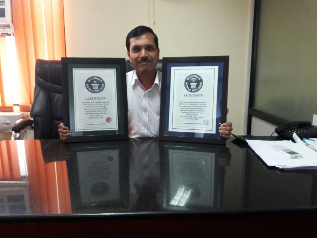 Manmohan Agarwal holding two framed world record certificates